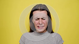 Young woman screaming in terror with hands on her head, mouth wide open in panic. Close up portrait of irritated female shouting.