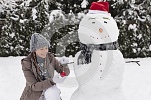 A young woman sculpts a snowman in her yard