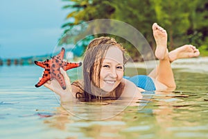 Young woman in the sea with red starfishes