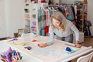 Young woman seamstress making pattern on fabric with tailors chalk. Girl working with a sewing pattern. Hobby sewing as a small bu