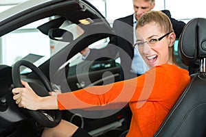 Young woman in seat of auto in car dealership