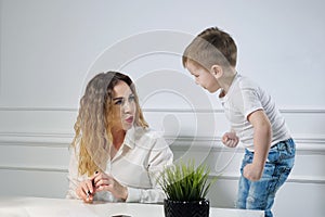 Young woman secretary with her little son in the workplace in office. Working mother.