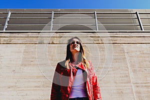 Young woman seen from below while she looks afar in industrial background