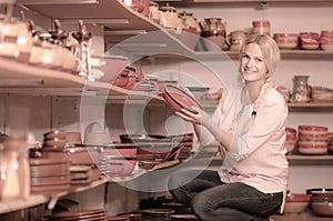 Young woman selecting ceramics with red enamel in atelier