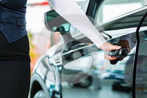 Young woman and seller with auto in car dealership