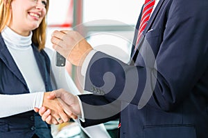 Young woman and seller with auto in car dealership