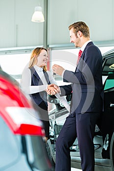 Young woman and seller with auto in car dealership