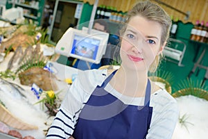 young woman selling fish at store