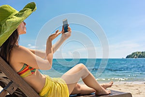 Young woman sending a love message through a selfie photo at the beach
