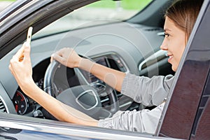 A young woman sends a message while driving her car