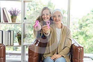 Young woman and senior breast cancer patient showing pink cancer ribbon, cancer concept