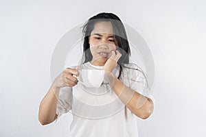 Young woman with sensitive teeth and cup of hot coffee at home