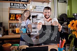 Young woman is serving the drinks and man is holding a sign