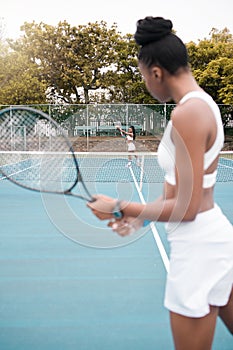 Young woman serving during a tennis match. Two women playing a game of tennis together. African american athletes