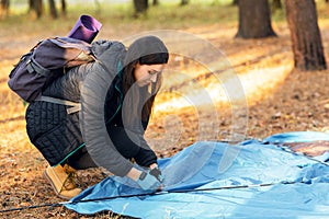 Young woman setting tent in camp, backpacking at countryside