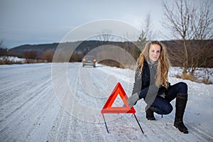 Young woman setting up a warning triangle and calling for assistance