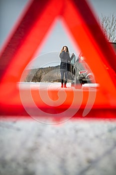 Young woman setting up a warning triangle and calling for assistence