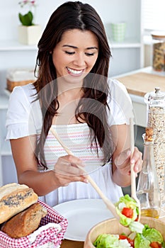 Young woman seving salad in kitchen photo