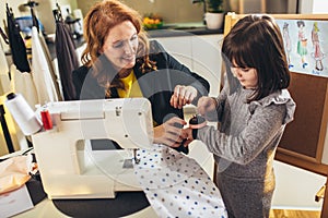 Young woman sewing with her daughter. She working at home