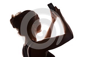 Young woman in a shade of a silhouette with phone