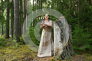 A young woman in the shape of a forest fairy in a forest with candles and a mask.