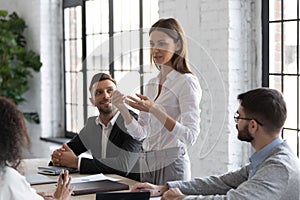 Young woman sharing opinion with colleagues during work meeting