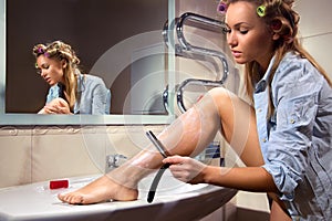 Young woman shaving her leg