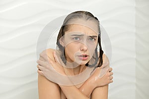 Young woman shivering with cold in the shower