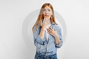 Young woman, shocked, covering her mouth with hands, on white background