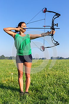 Young woman shooting arrow of compound bow