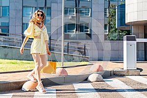 Young woman shopaholic wearing yellow summer costume holds bag