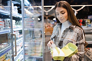 Young woman shopper in the grocery store choosing fresh chicken eggs.