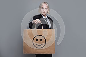 Young woman with shopping bag with icon smile emoticon on grey background