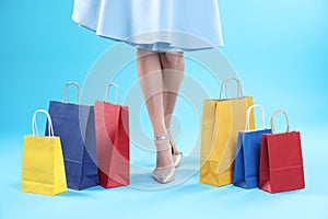 Young woman with shopping bags on color background