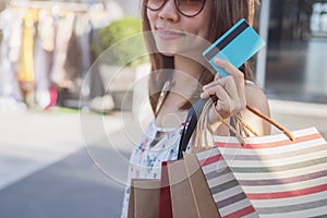 Young woman with shopping bags and credit card at shopping mall