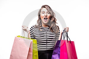 Young woman with shopping bags over white background screaming and wondering