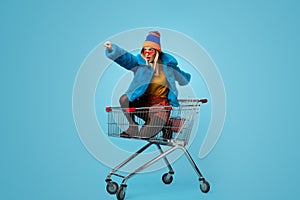 Young woman with shopping bags riding trolley