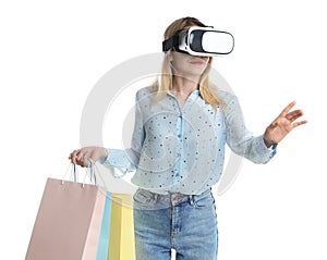 Young woman with shopping bags using virtual reality headset on white background