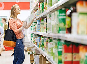 Young woman shopping for juice in supermarket