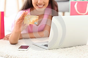 Young woman shopping online with credit card and laptop at home