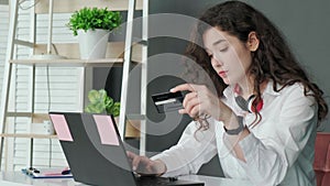 Young woman shopping online with credit card using computer at home.