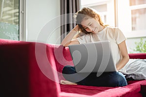 Young woman shopping online with internet in happy mood on red sofa. Business and working concept, Relax and part time concept