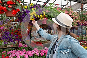 Young woman shopping in an outdoors fresh urban flowers market, buying and picking from a large variety of colorful floral