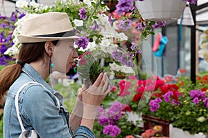 Young woman shopping in an outdoors fresh urban flowers market, buying and picking from a large variety of colorful floral