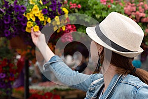 Young woman shopping in an outdoors fresh urban flowers market, buying and picking from a large variety of colorful floral