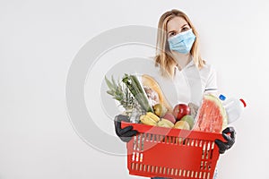 Young woman shopping during a pandemic. Girl in medical mask with basket of products. Shopping times Covid-19