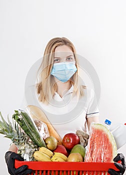 Young woman shopping during a pandemic. Girl in medical mask with basket of products. Shopping times Covid-19