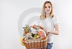 Young woman shopping during a pandemic. Girl in medical mask with basket of products. Shopping times Covid-19