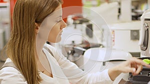 Young woman shopping in store buying kitchen appliances. Picking up deep fryer grille. White goods on background