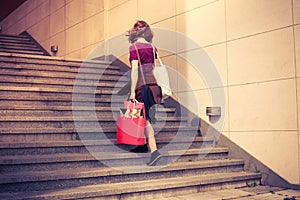 Young woman with shopping walking up stairs